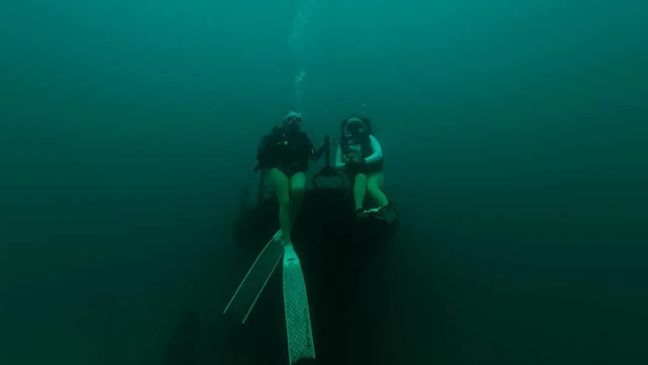 Two divers on a shipwreck in the green water off Trincomalee
